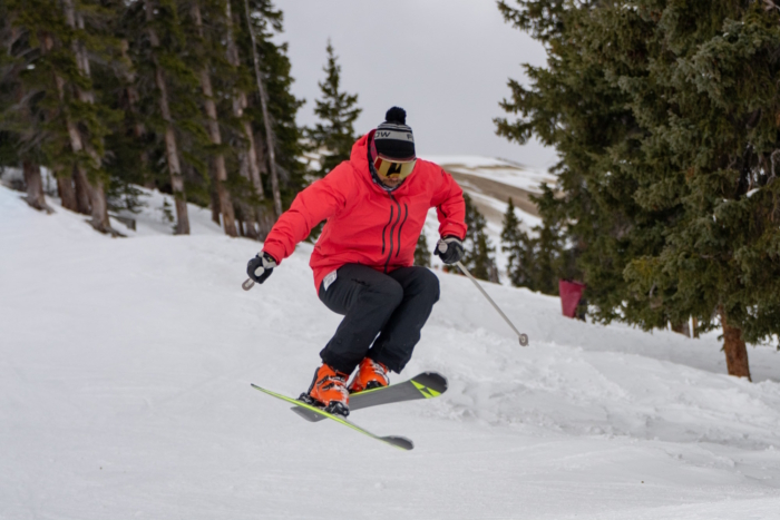 Skier in a red jacket jumping with Fischer RC One 86 GT RSW12 skis on a snowy slope