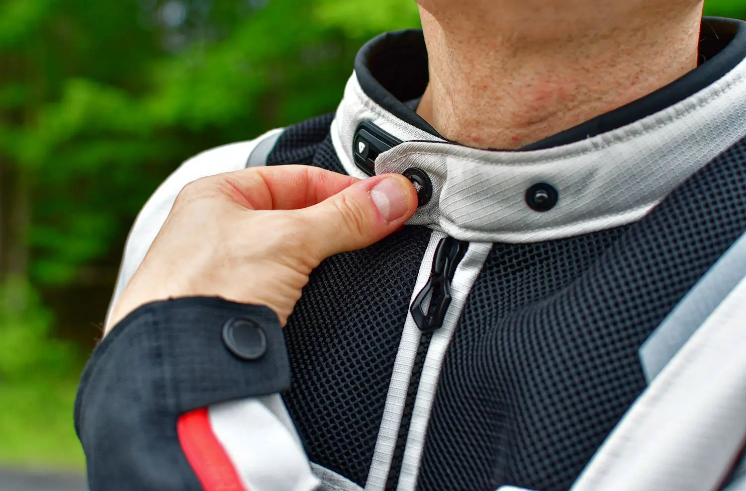 A person fastening the collar of a REV'IT! Tornado 4 H20 jacket
