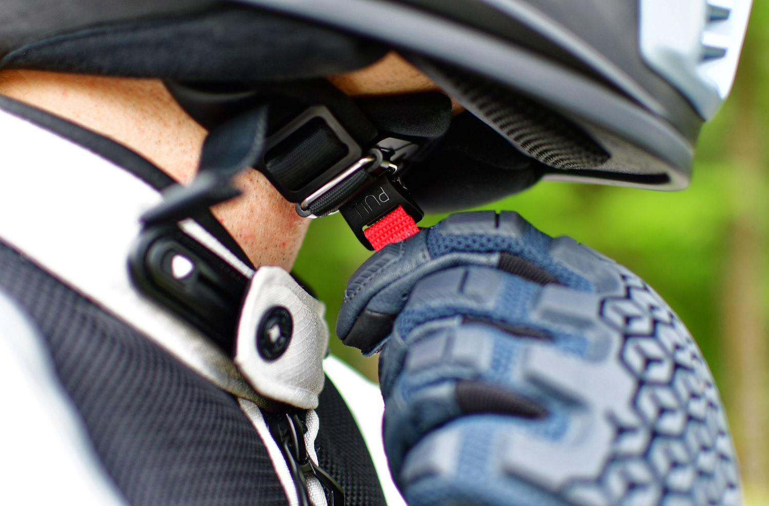 A motorcyclist adjusting helmet chinstrap
