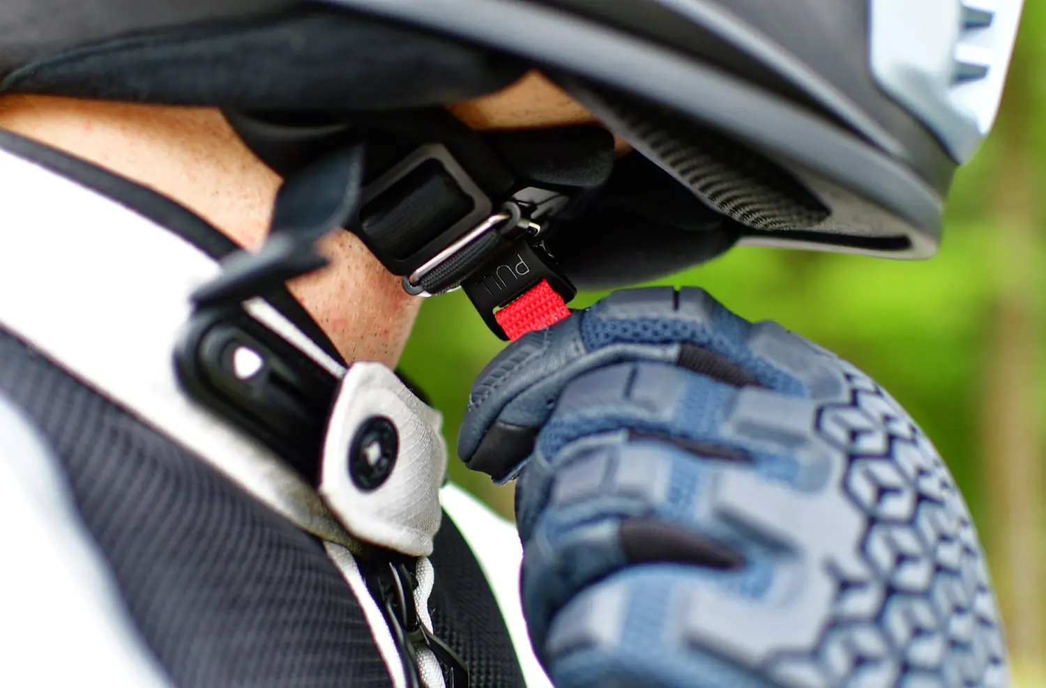 A motorcyclist adjusting helmet chinstrap
