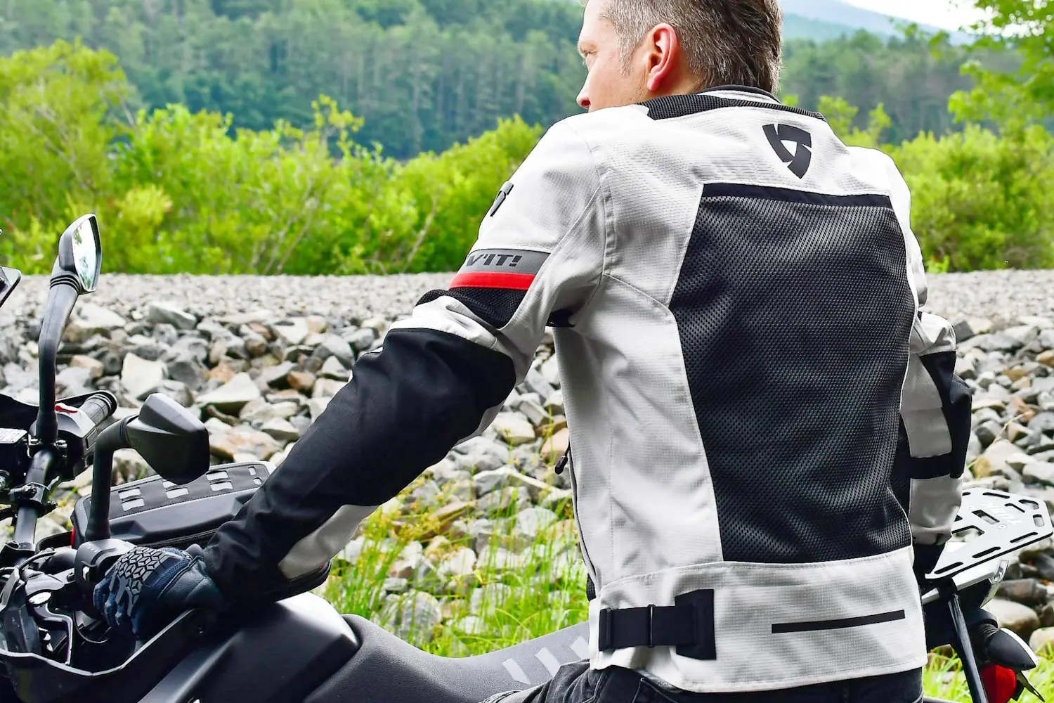 Motorcyclist in a REV'IT! jacket, viewing a mountain landscape