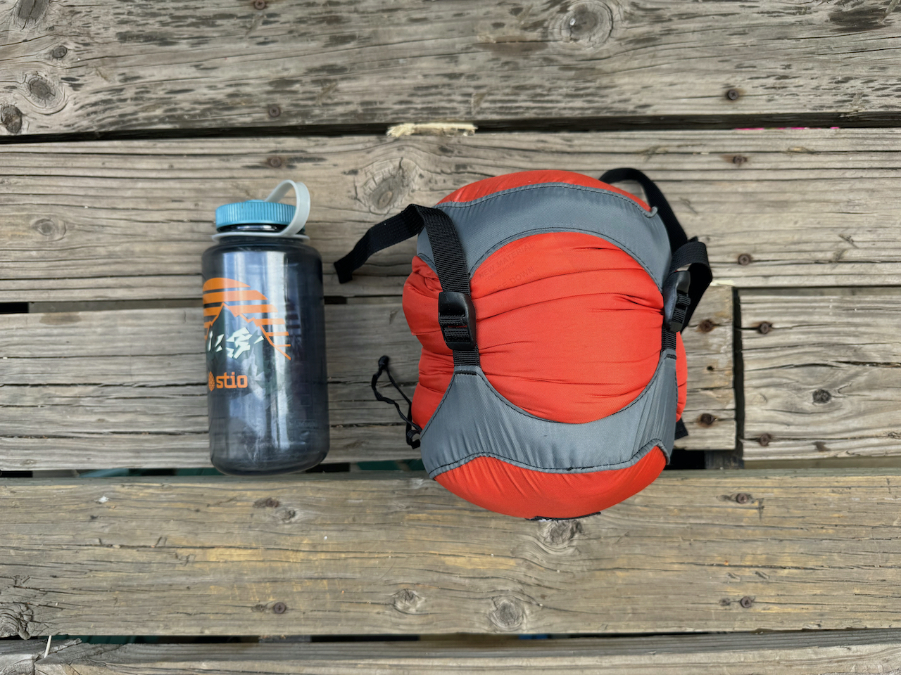 packed alpinlite sleeping bag next to water bottle