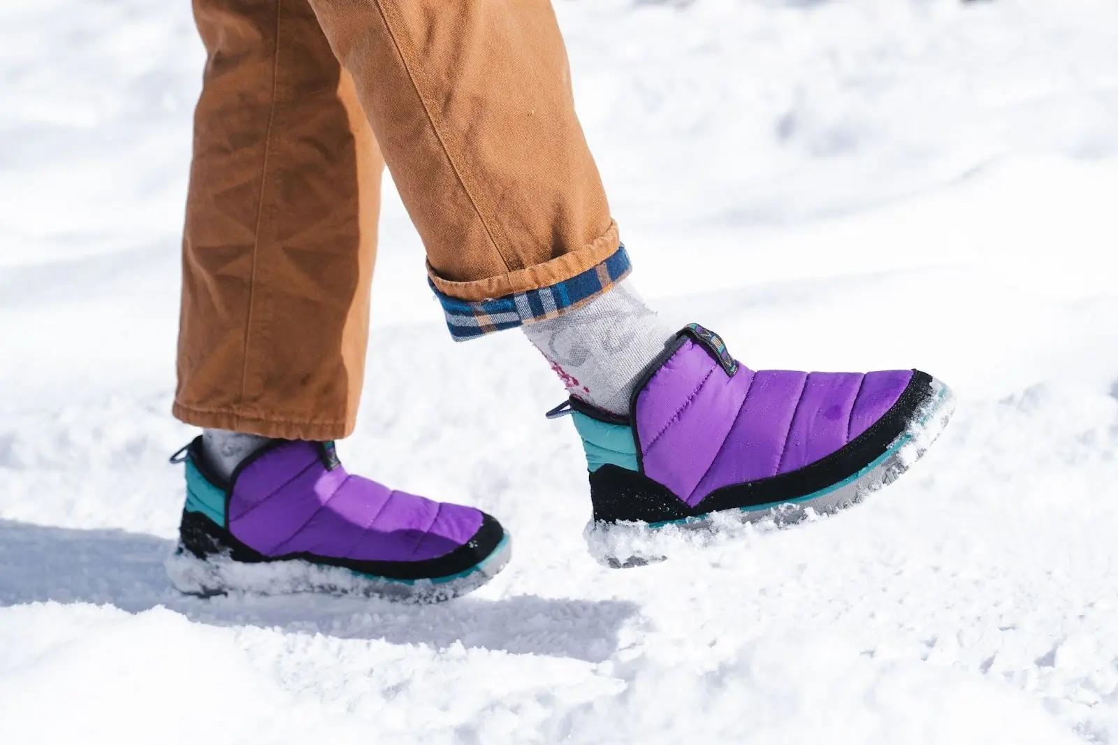 woman walking on snow while wearing purple l.l. bean mountain classic quilted bootie
