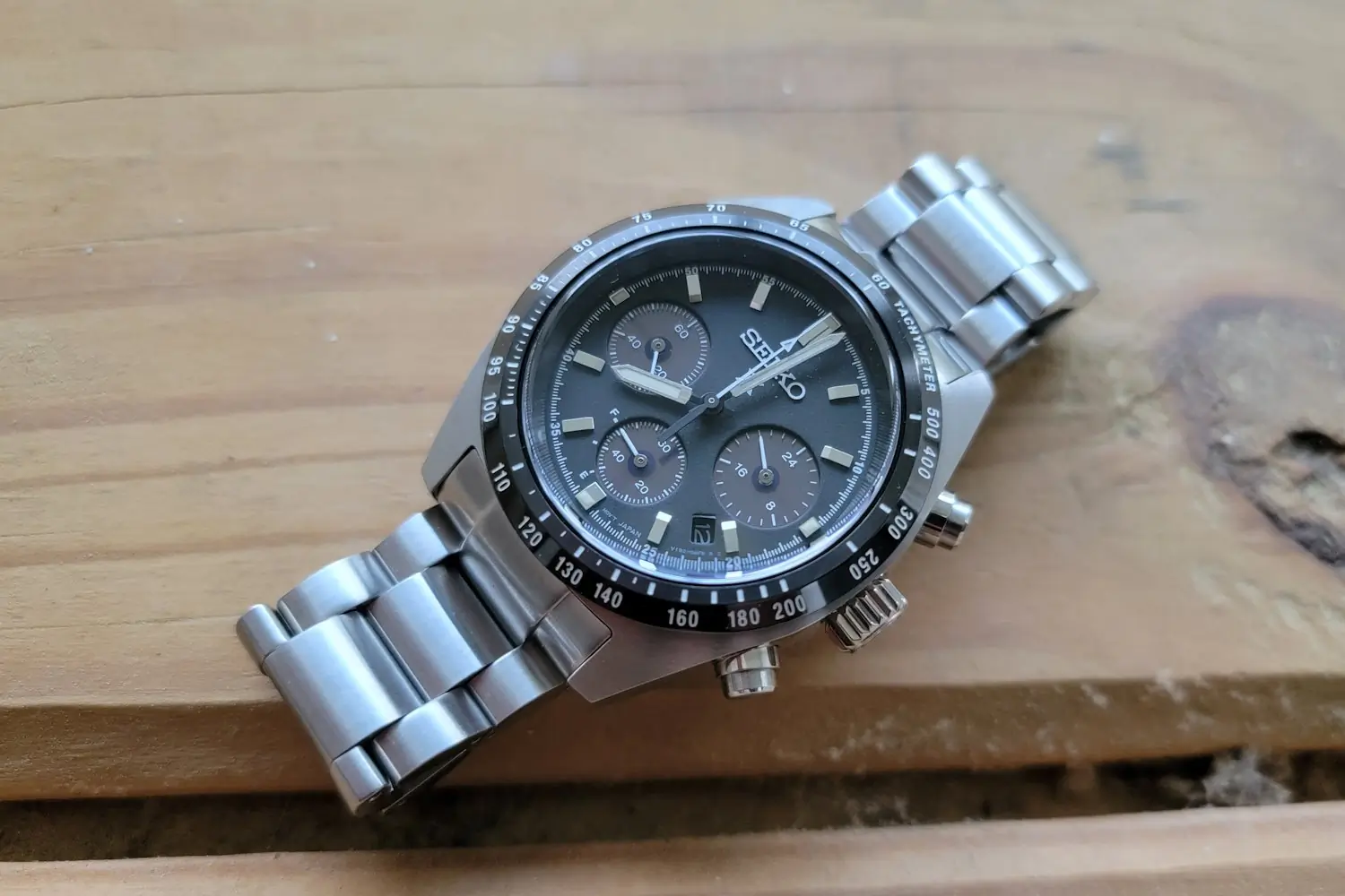 Seiko Prospex Speedtimer chronograph watch with a stainless steel bracelet, placed on a wooden surface