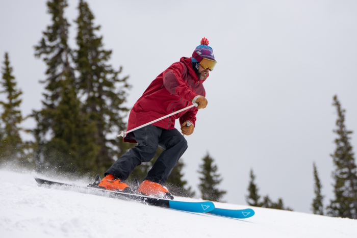 A skier in a red jacket navigates a snowy slope on Renoun Endurance 98 skis, demonstrating excellent control and technique