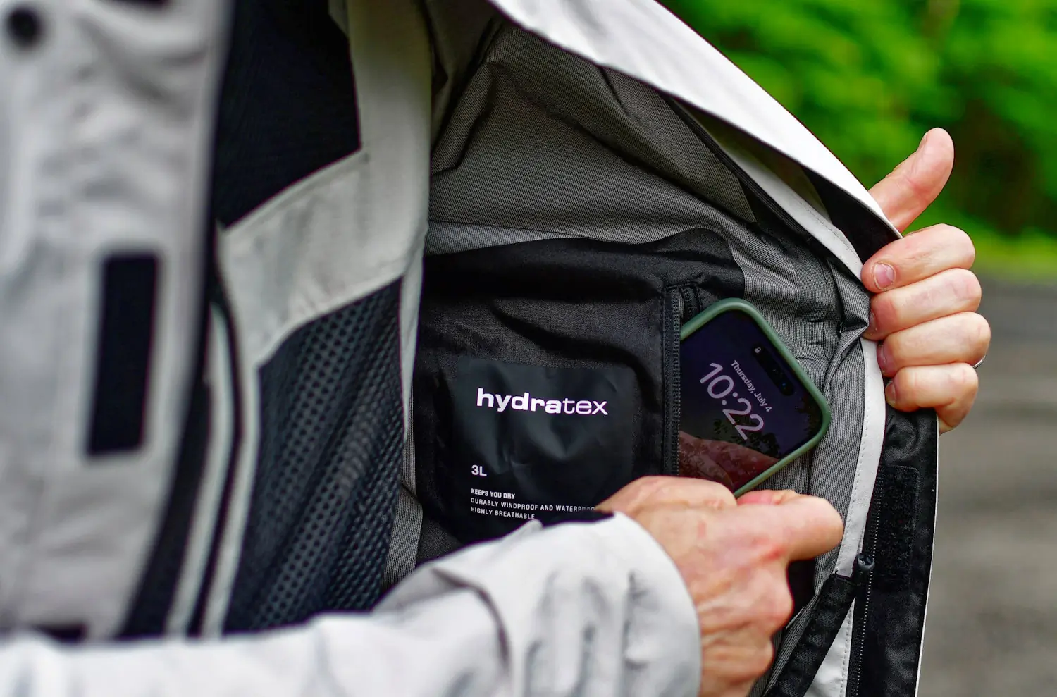 A person opens their Tornado-4-H2O jacket labeled 'hydratex,' revealing a phone inside
