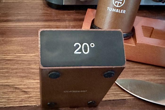 A metal block labeled "20°" on a wooden surface, next to a knife