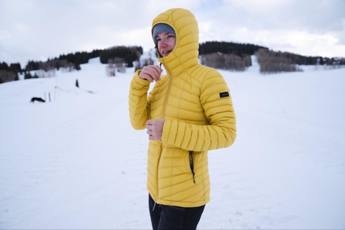Woman adjusting the jacket zipper while standing in a snowy field