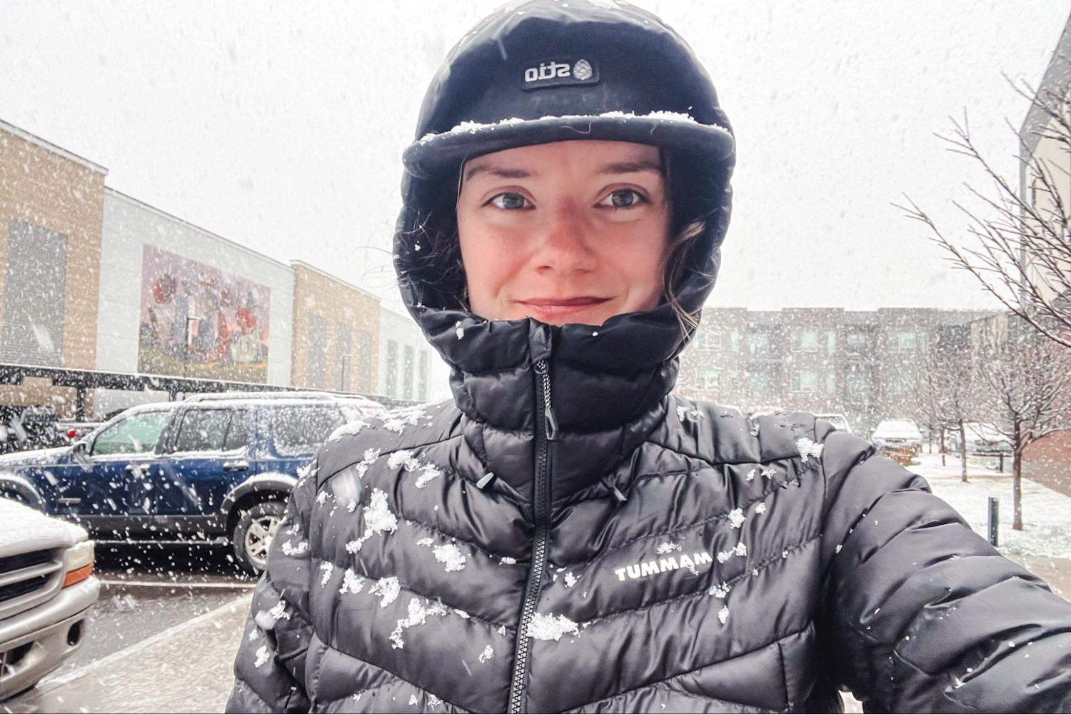 Person wearing a black puffer jacket with snowflakes falling on them