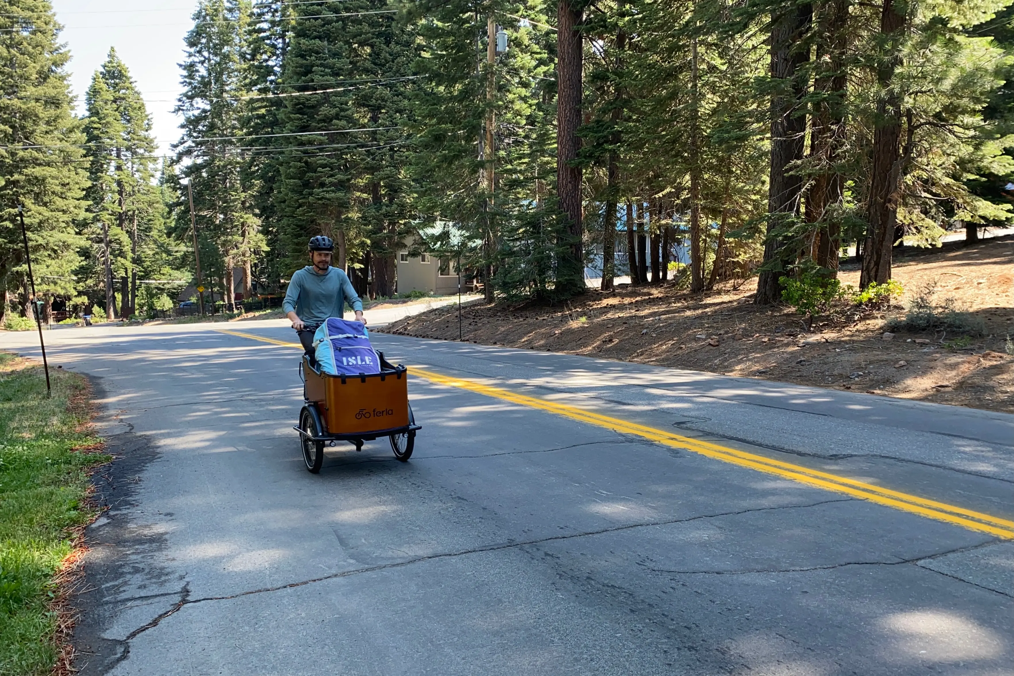 The author riding up a hill on the Ferla Royce 2 electric cargo bike with an inflatable paddleboard in the cargo box