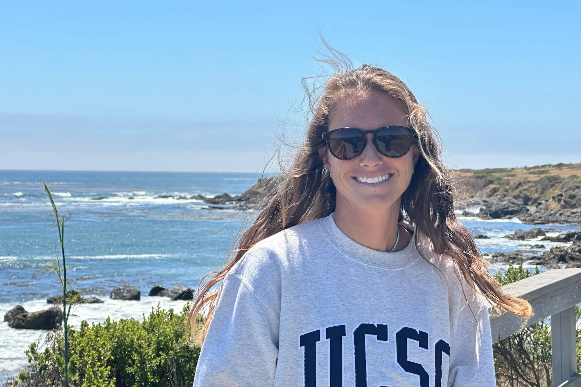 Rebecca Parsons wearing the Smith Optics Wander sunglasses in casual attire at a vista with the Pacific ocean behind her