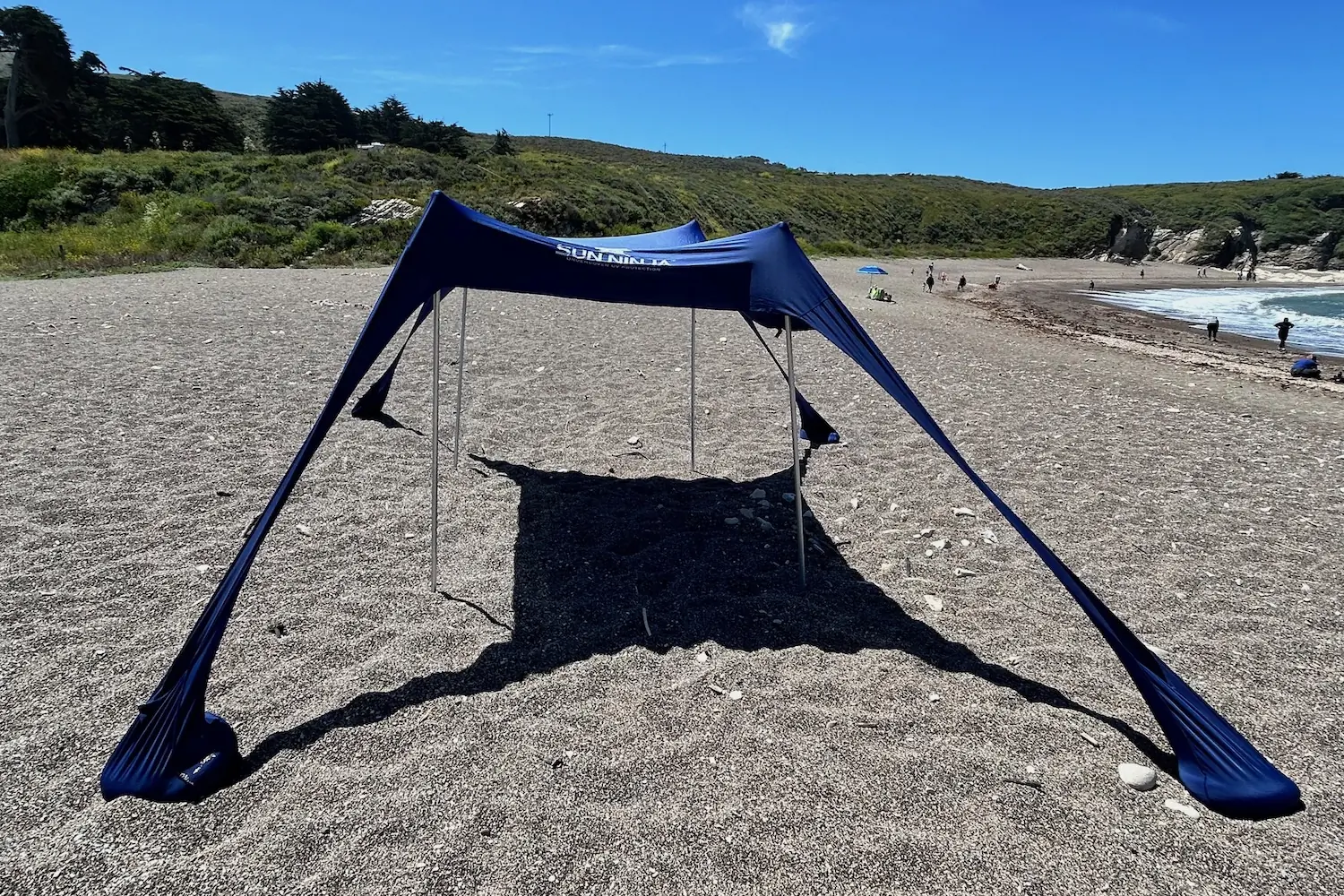 The Sun Ninja tent set up on a pebbly beach on the California coast