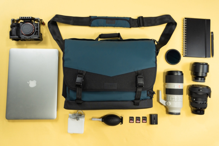A flat lay of camera gear, including lenses, a MacBook, a camera, and accessories
