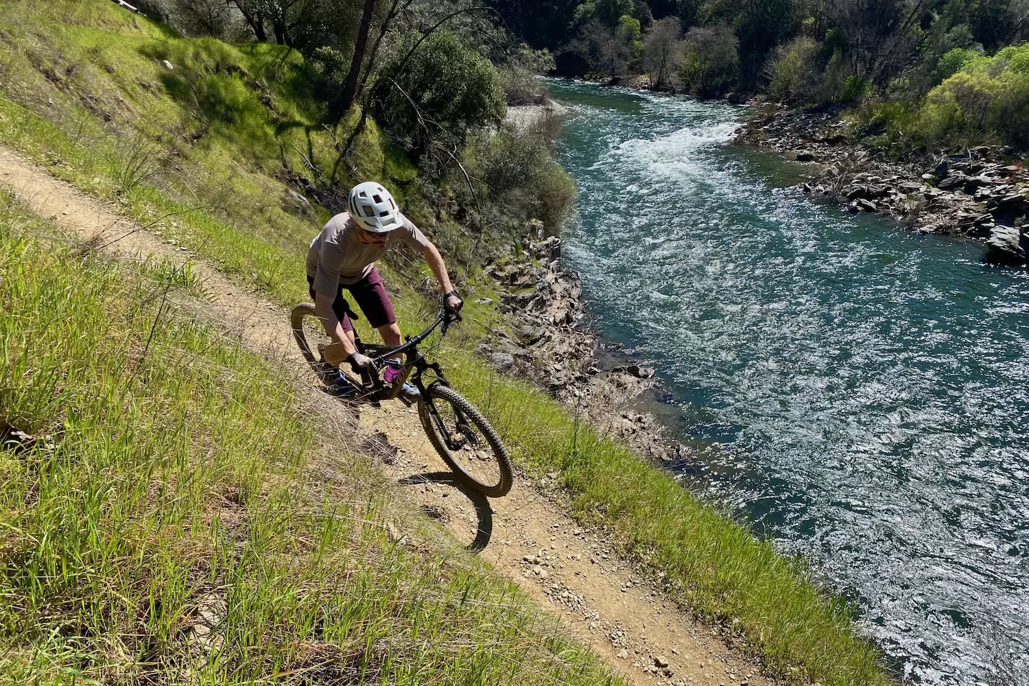 The author riding above a river on a singletrack trail while testing mountain bike shorts