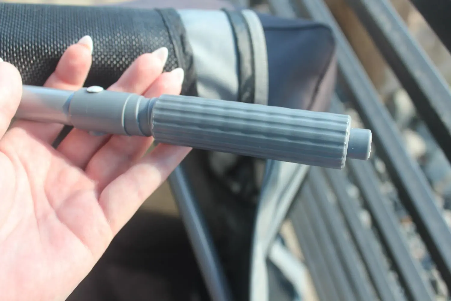 Close-up of a hand holding a gray ribbed handle with twistable locking mechanism
