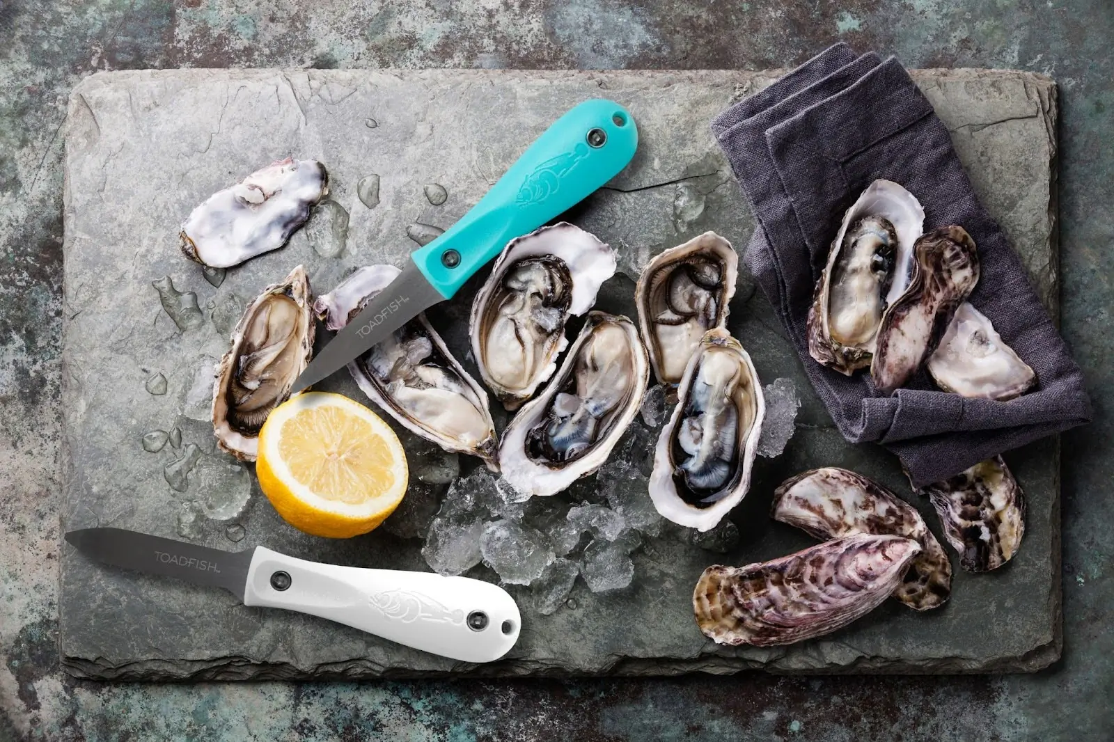 toadfish oyster knife and pro oyster knife on a board full of oysters