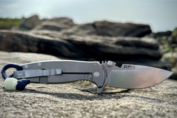 A DPx Gear HEST/F 4.0 folding knife lies open on a rock
