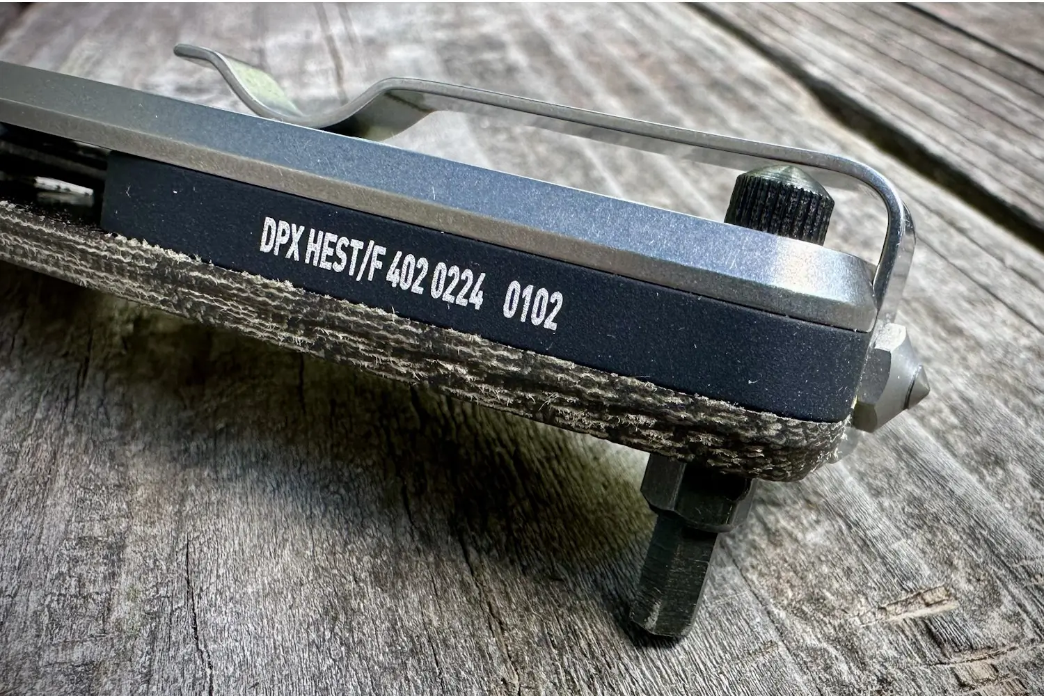 Close-up of the DPx HEST/F 4.0 knife handle with model and serial number, showing the hex drive and pocket clip