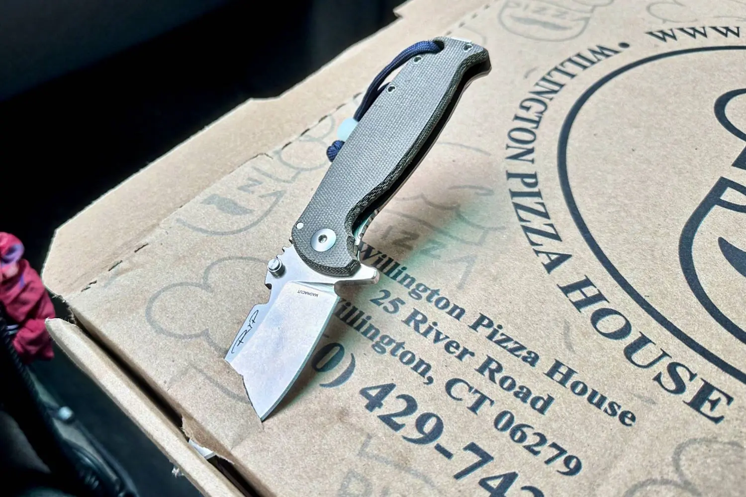 The HEST/F 4.0 knife stabbed into a pizza box lid