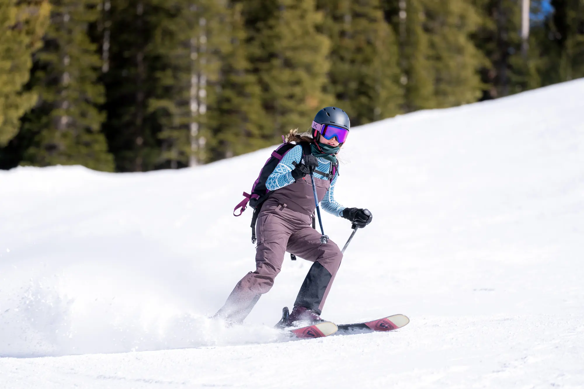 female skier descending in ski bibs and base layer top