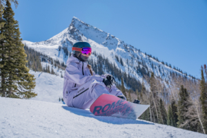 snowboarder sitting with Mount Crested Butte in the background