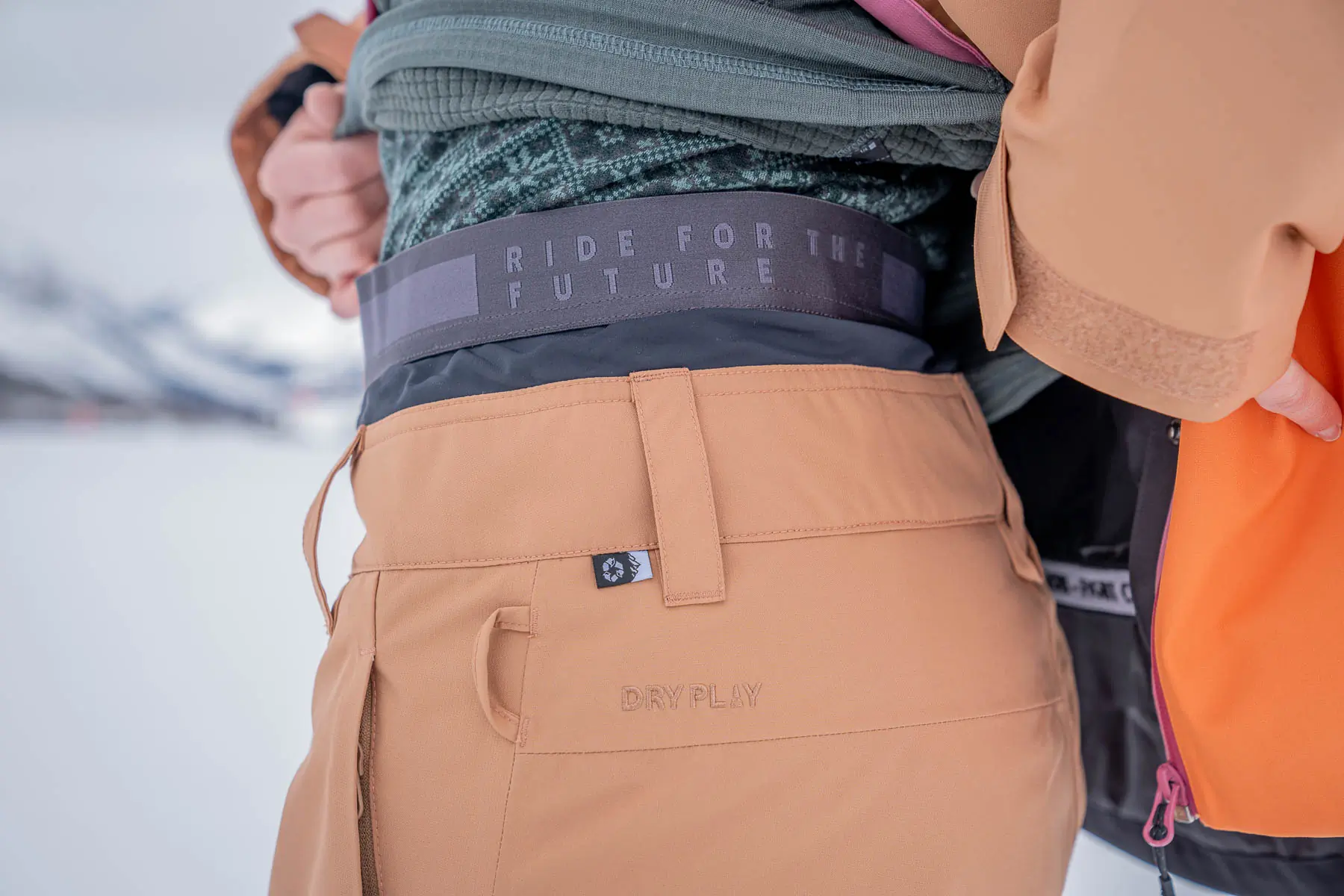 side of woman wearing snowboard pants, base layer top and mid layer top