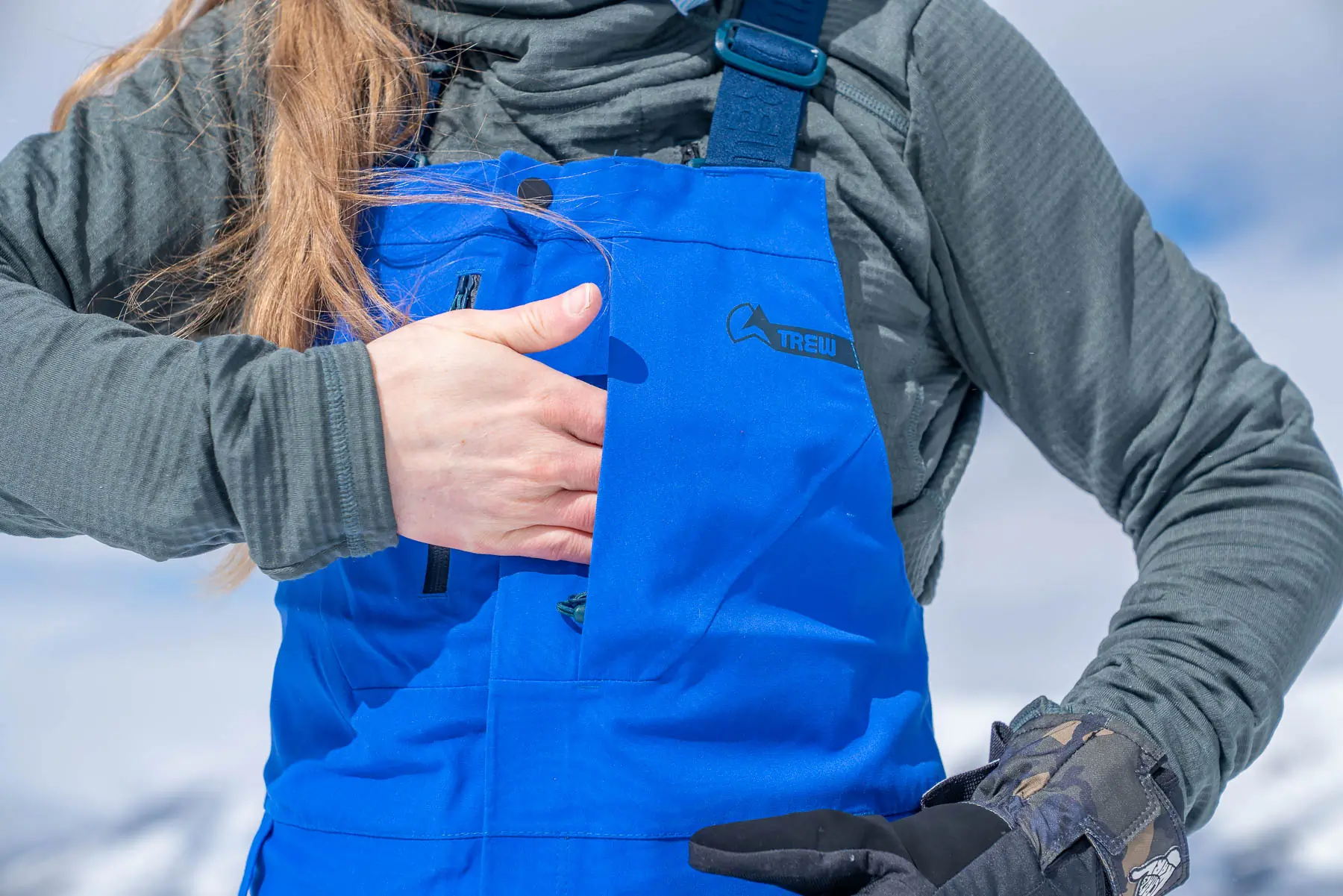 woman sliding hand into chest pocket on TREW bibs