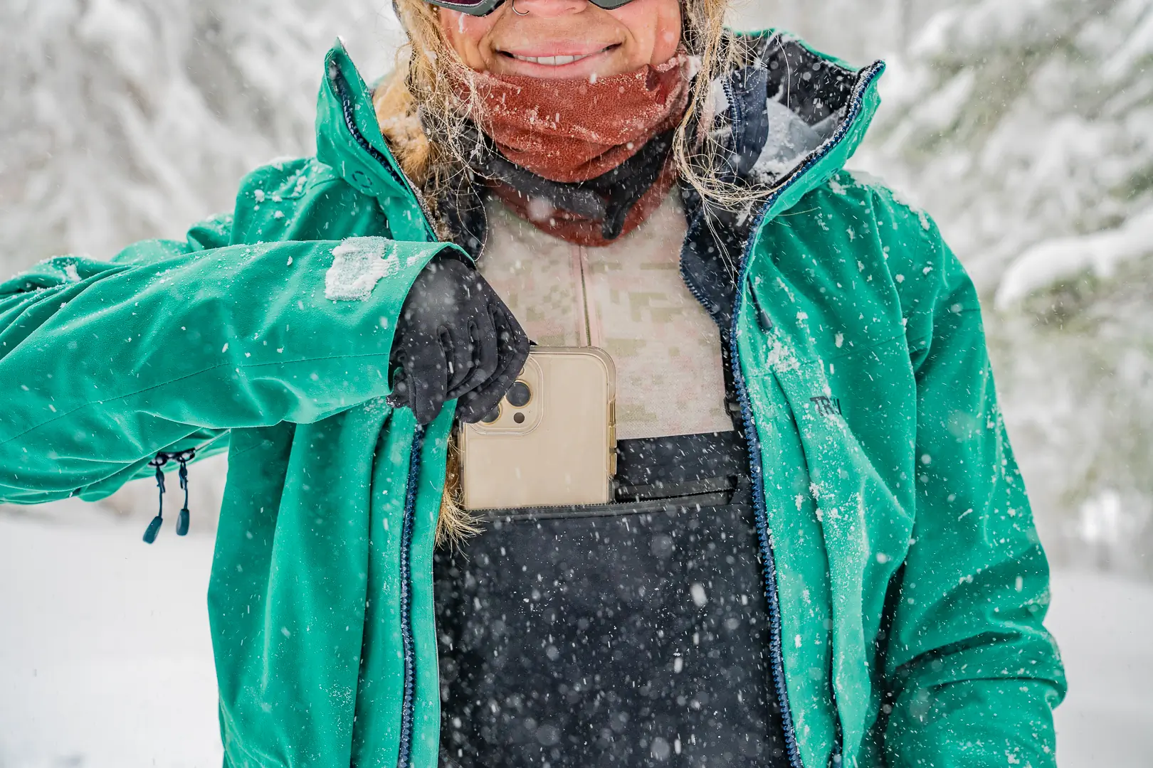 woman sliding phone out of chest pocket on ski bibs