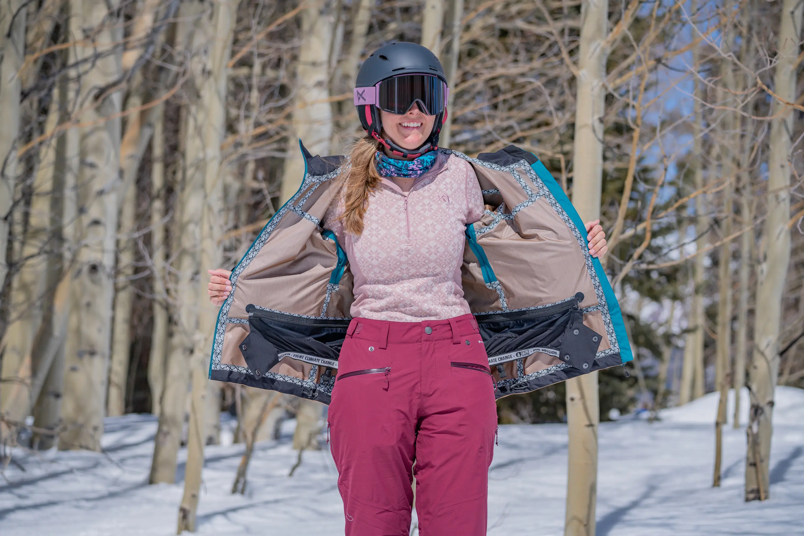 woman pulling open ski jacket and wearing long sleeve base layer