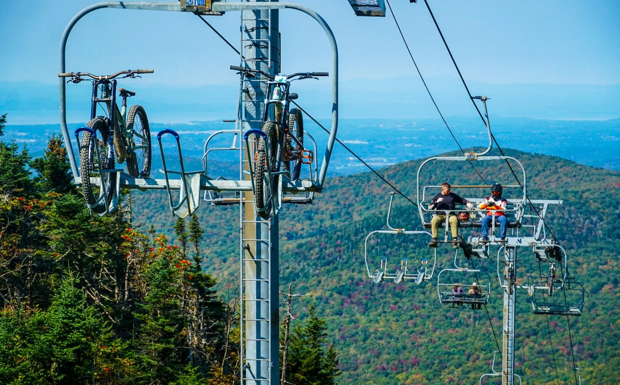 Mountain bikers riding up a chair lift at Bolton Valley Resort.
