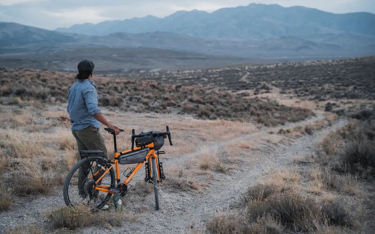 A person stands beside a yellow REI ADV 2.2 bike gazing at Humboldt Mountain