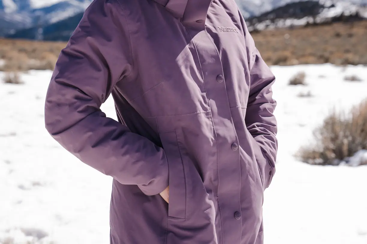 woman resting hands inside jacket packets of winter jacket 