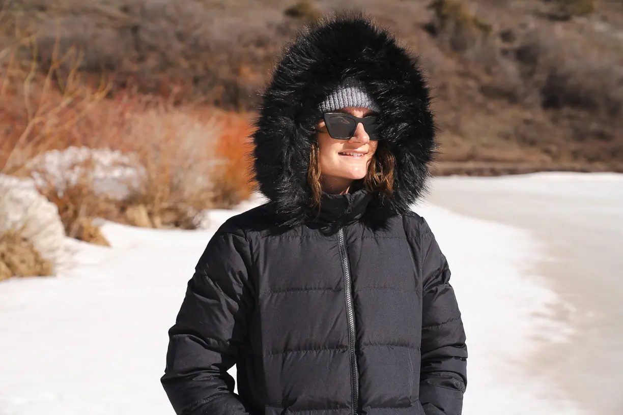 woman testing jacket with faux fur on hood