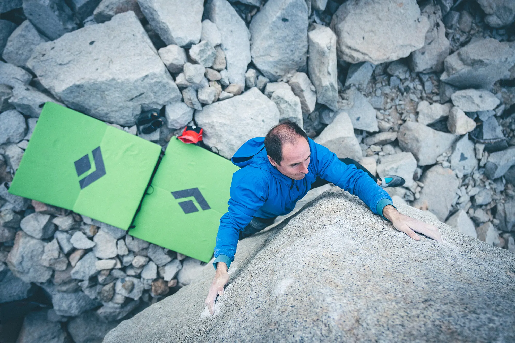 man climbing and in the background black diamond erratic crash pad
