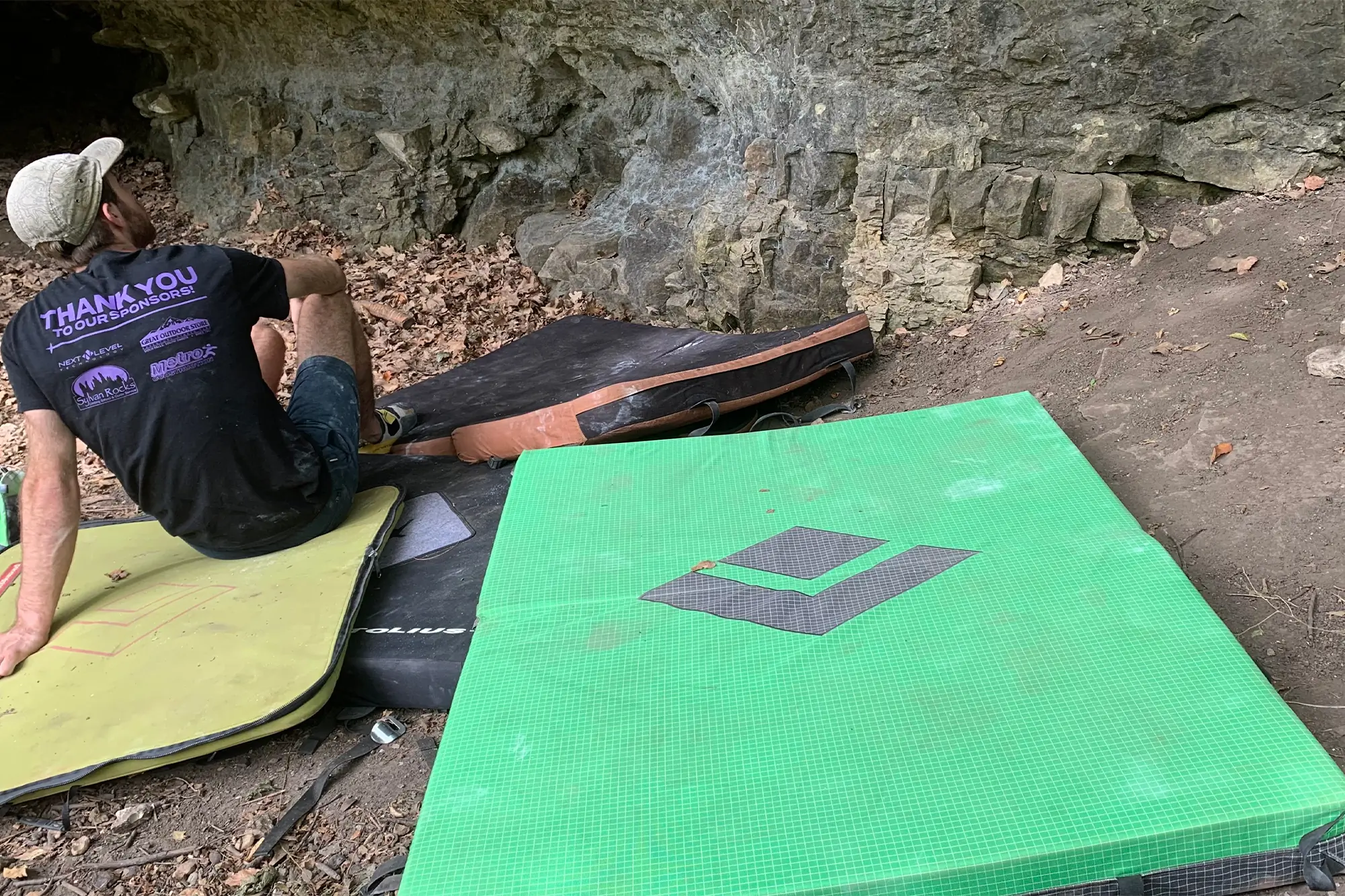 man sitting next to the black diamond erratic crash pad