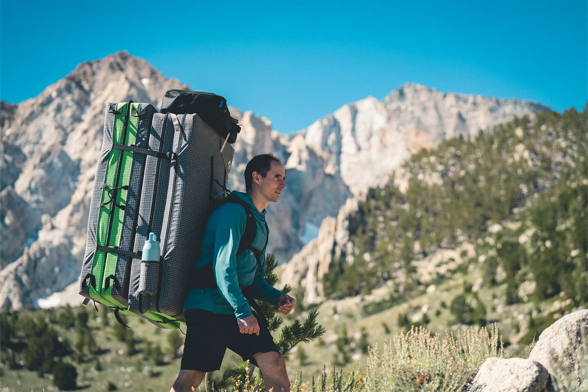 man carrying black diamond erratic crash pad on his back