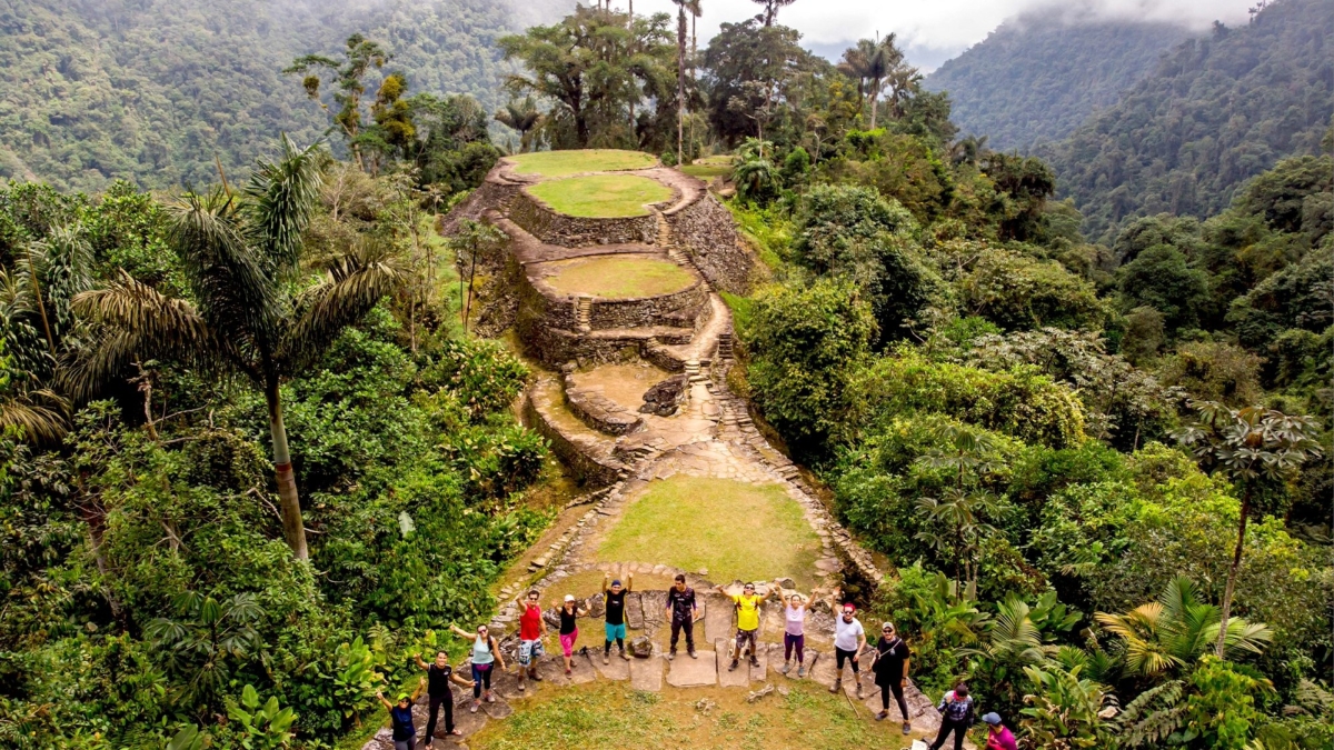 a group of tourists stands together in the foreground, with the ancient ruins of the Lost City in the background