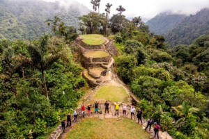 a group of tourists stands together in the foreground, with the ancient ruins of the Lost City in the background