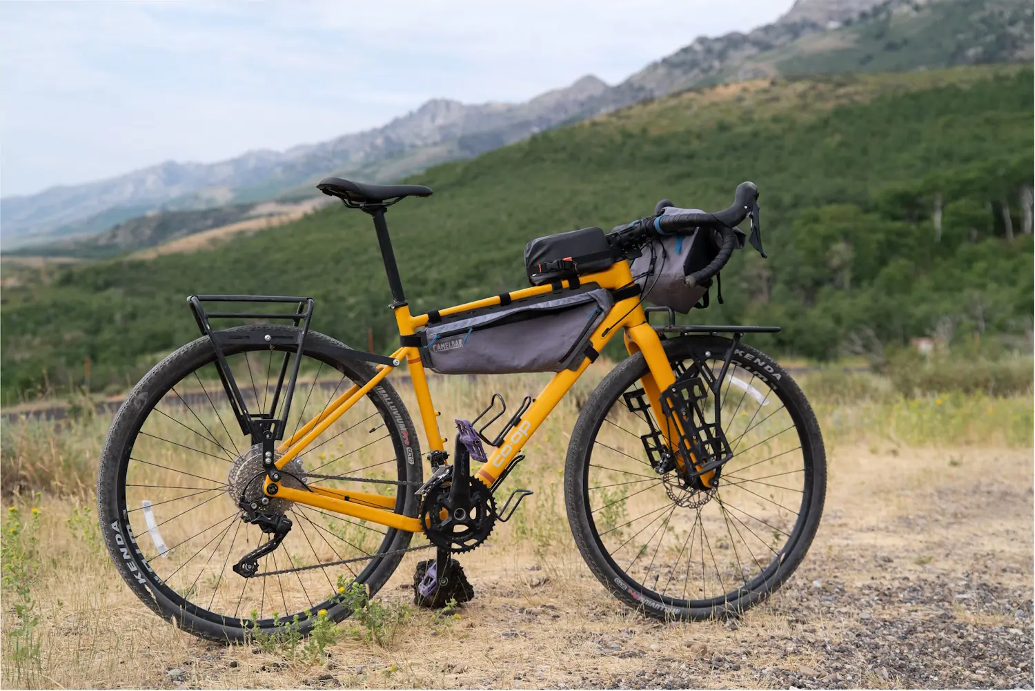 REI Co-op ADV 2.2 bike with racks and bags, parked on a gravel path