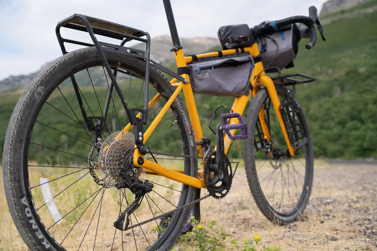 Yellow REI Co-op ADV 2.2 bike with racks and bags on a gravel path