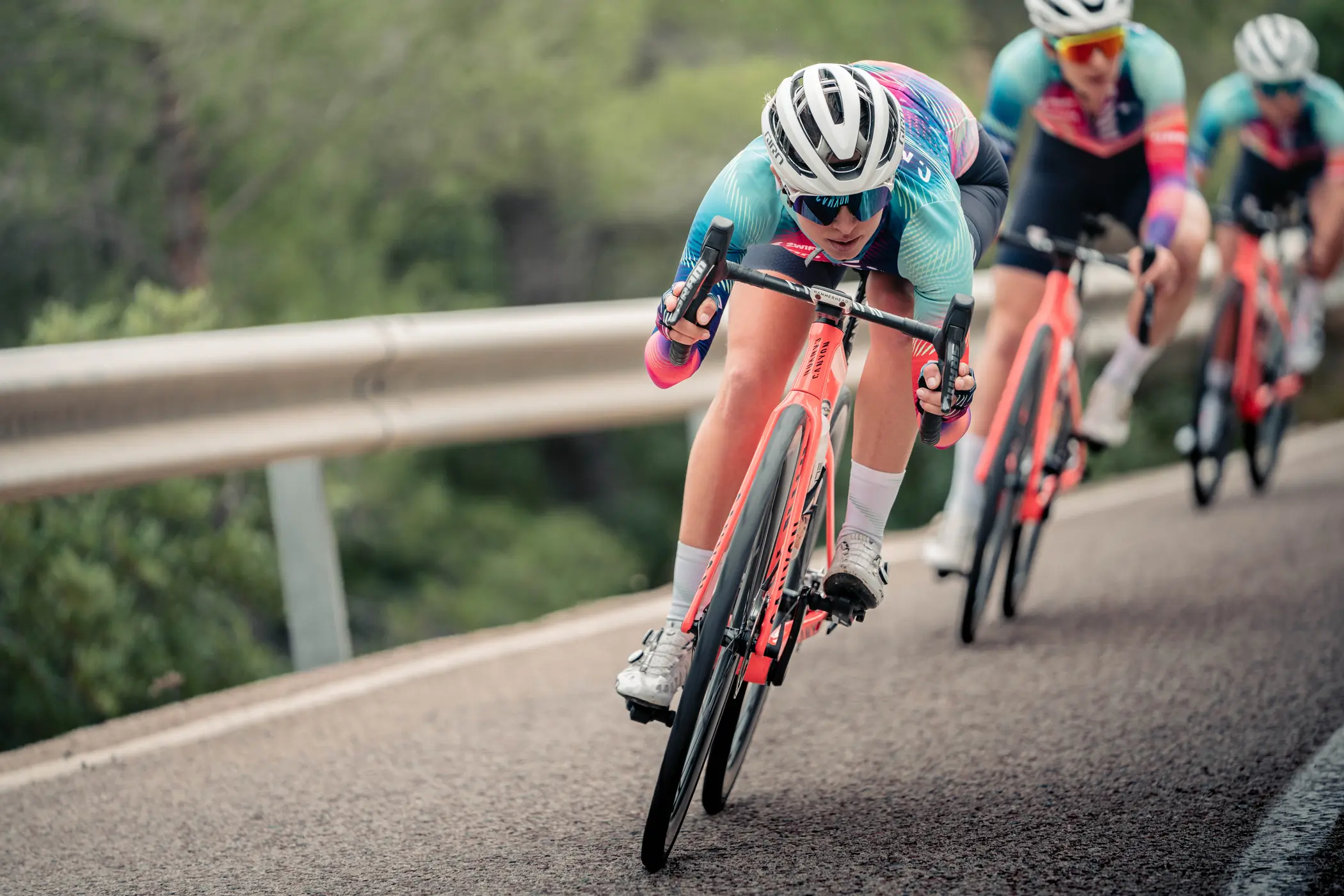Kasia Niewiadoma in an aero tuck while descending with her team on a road.