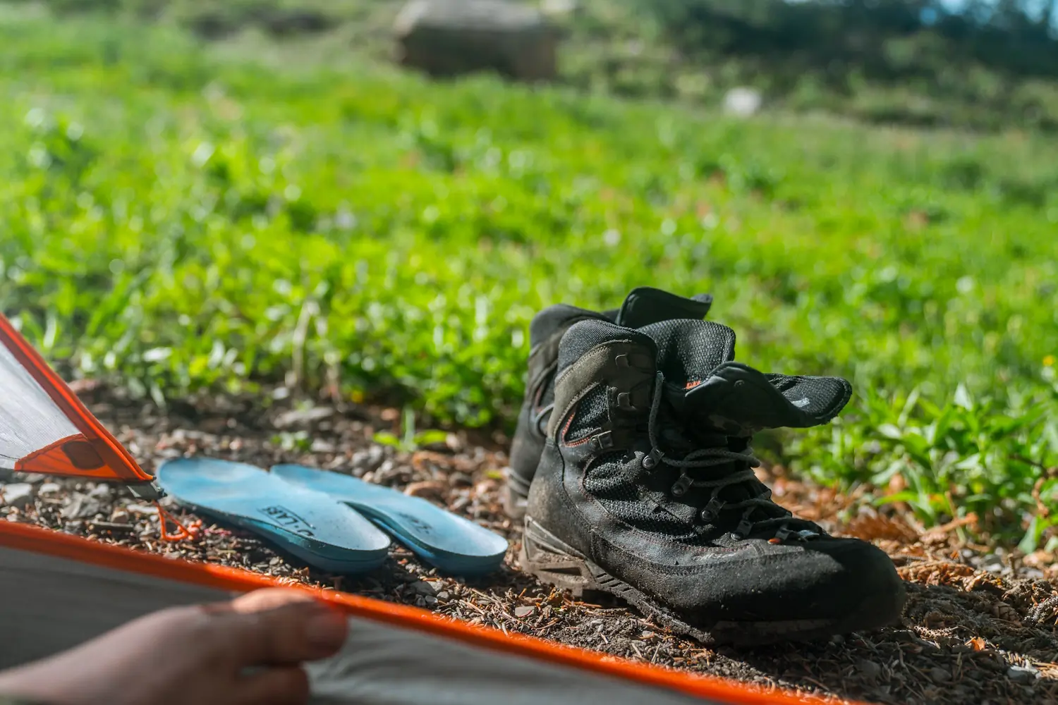 Black hiking boots and blue insoles placed on the ground