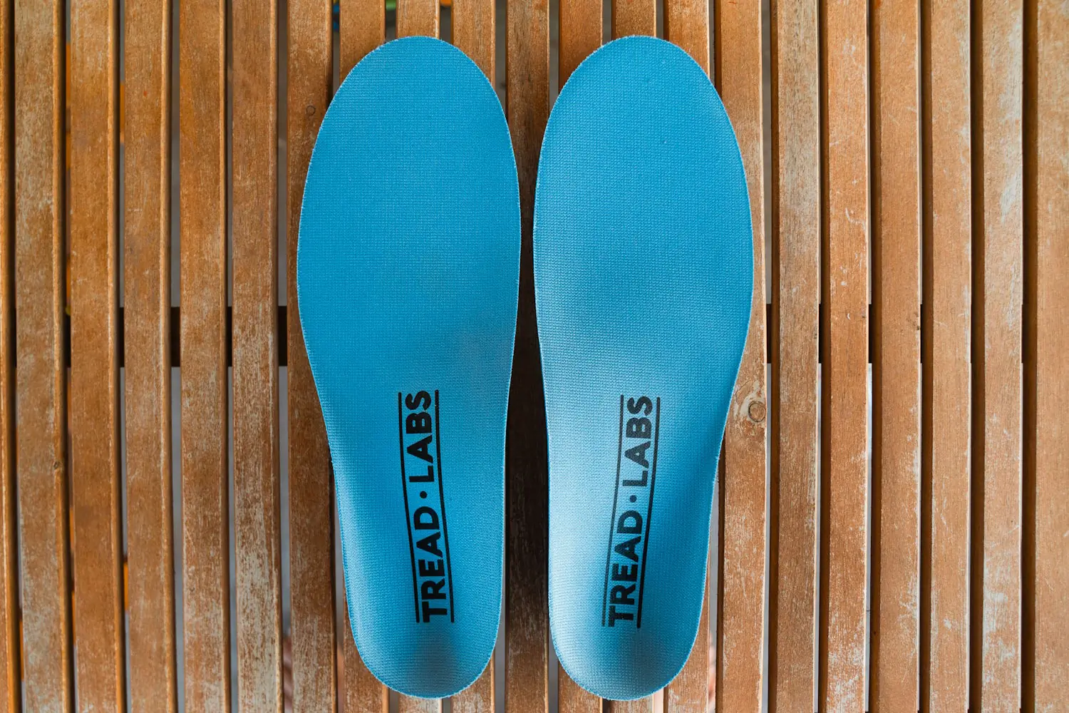 Pair of Tread Labs insoles placed on wooden surface