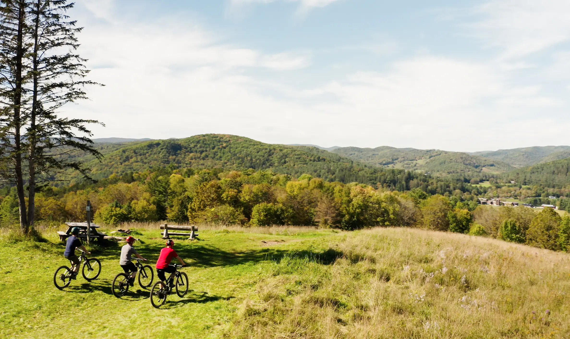 Three mountain bikers riding over hilly terrain.