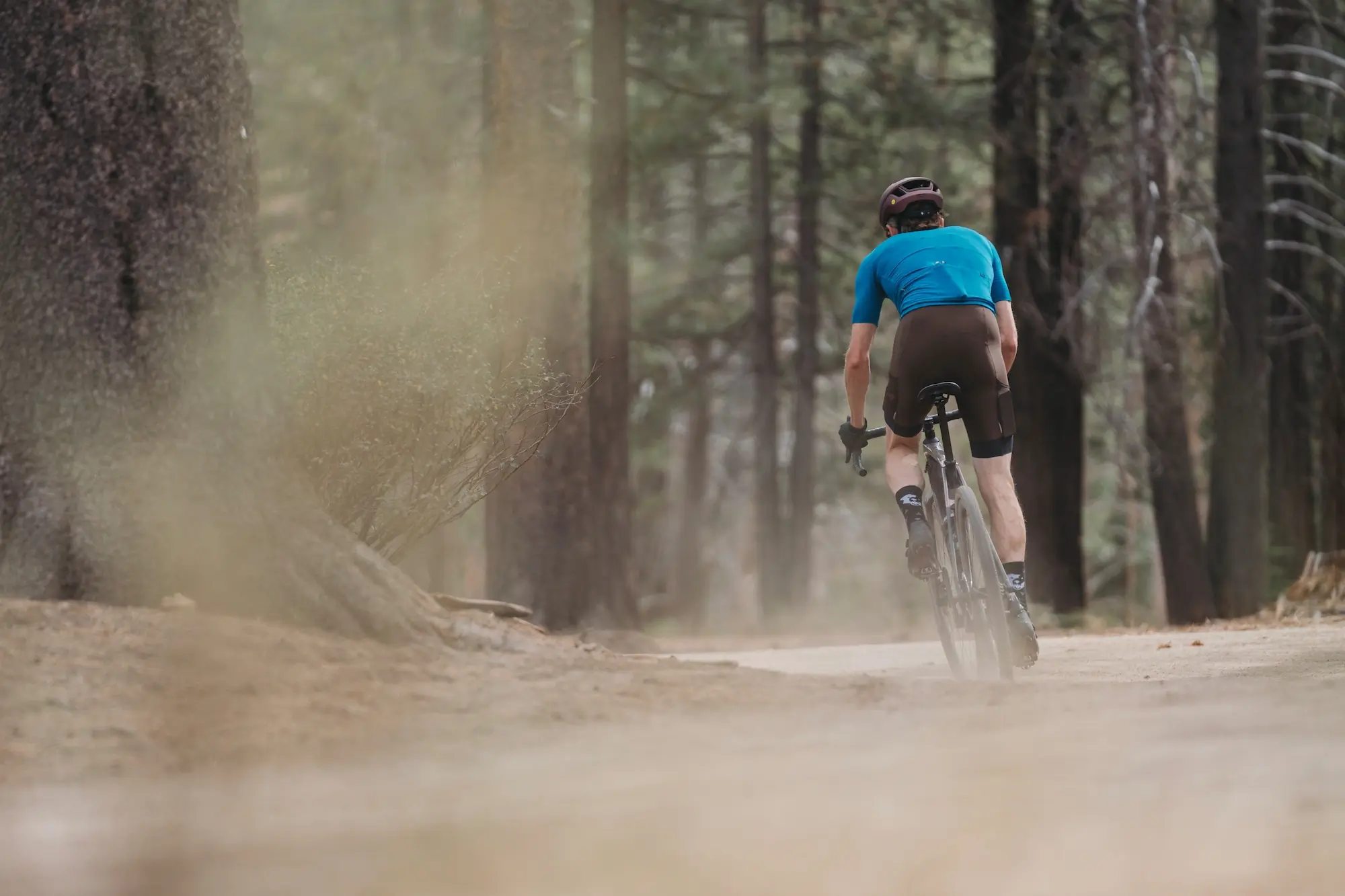 A rider wearing the Ornot Cargo bibs while riding a gravel bike in the forest