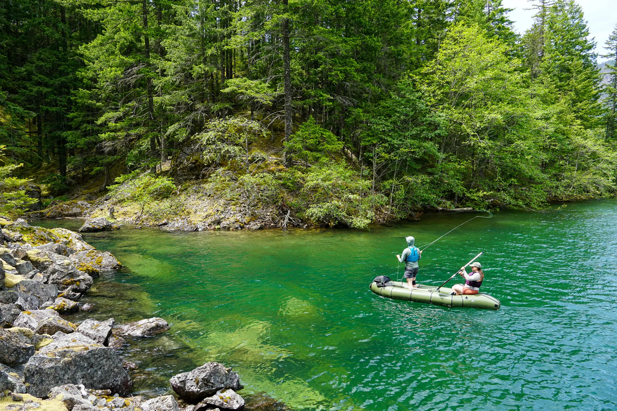 a paddler makes casts with a fly rod from the rendezvous while the rear paddler keeps the raft moving