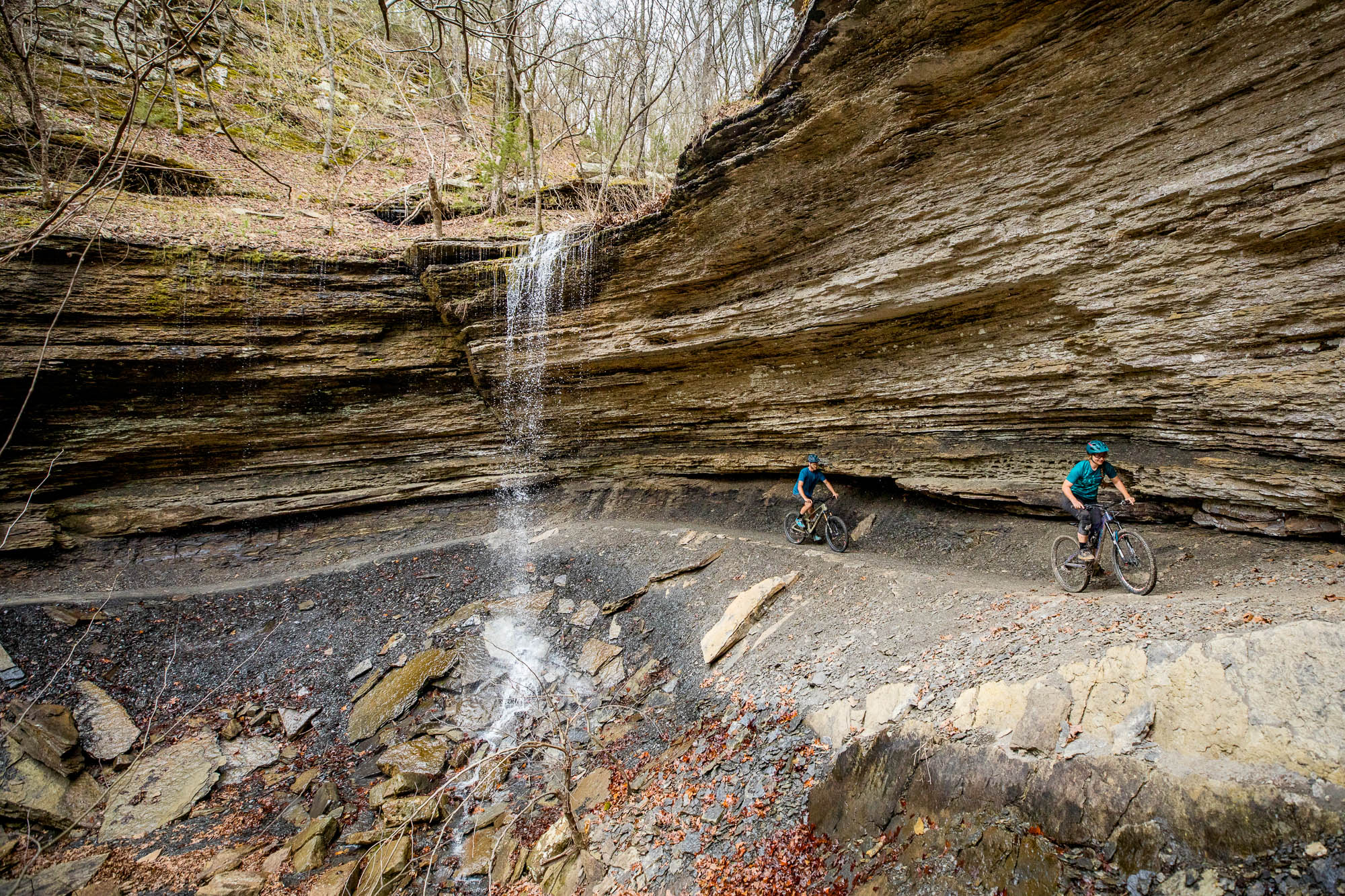 Mountain biking under sandstone cliffs and waterfall in Northwest Arkansas
