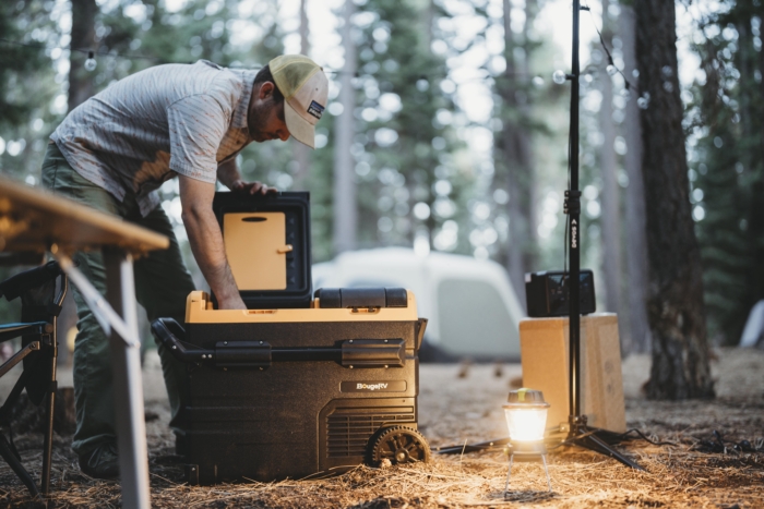 handsome man reaches into the BougeRV CRD45 electric cooler to grab a brewski