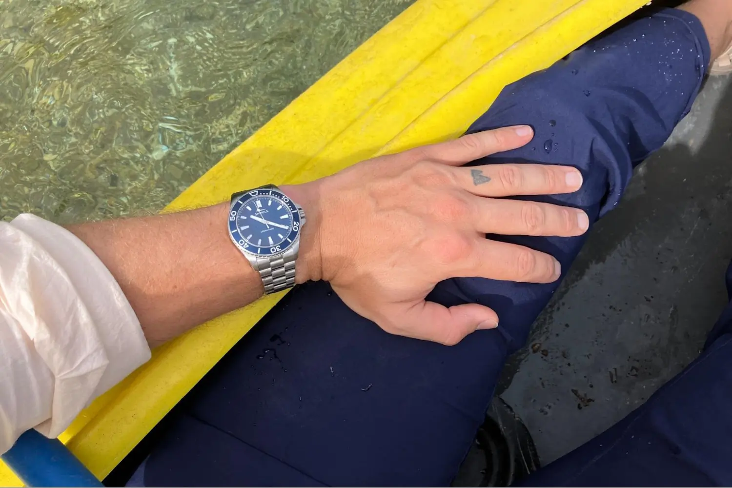 A Lake Michigan Monster watch on a wrist rests on the edge of a yellow boat