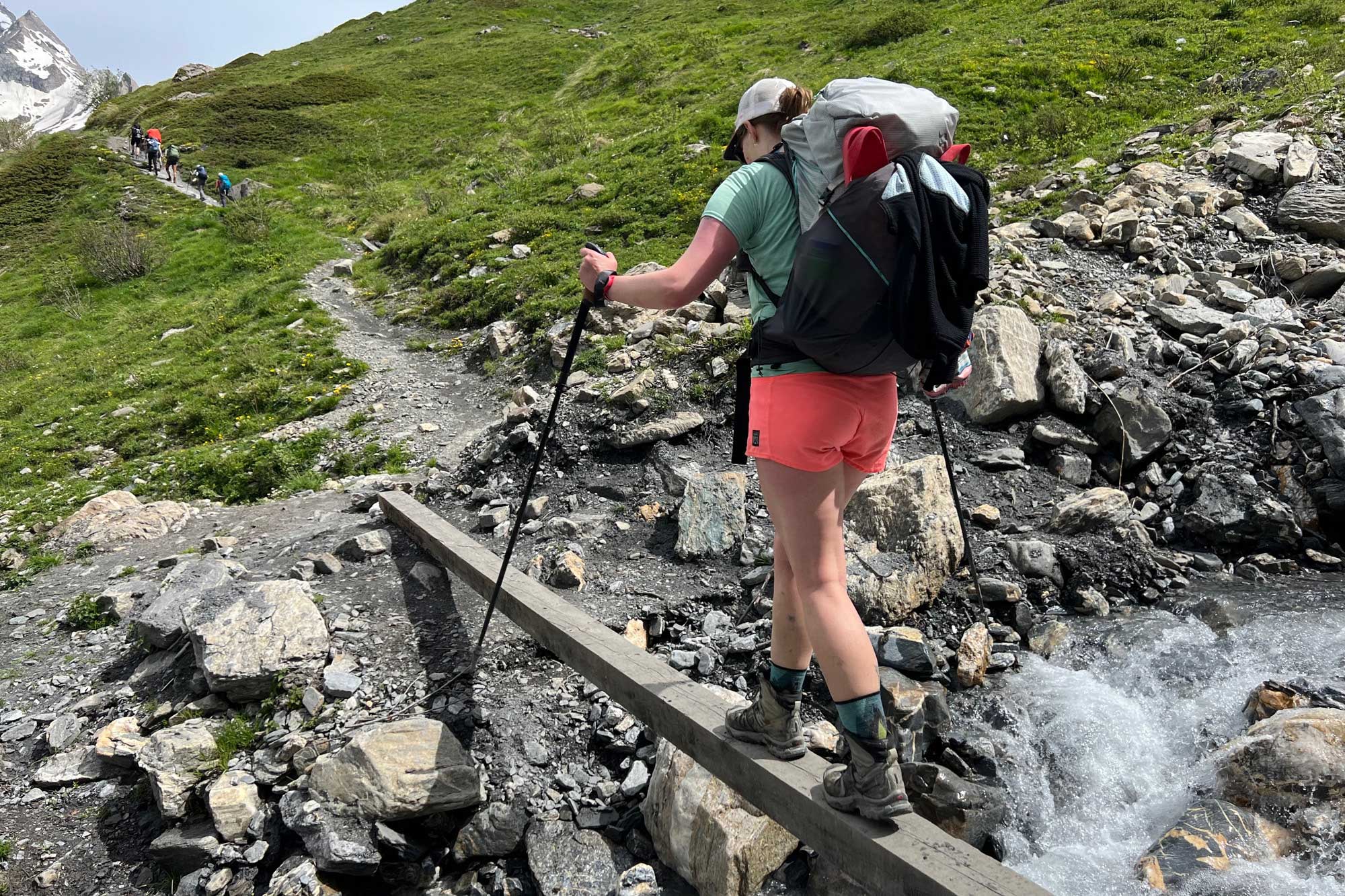Woman crossing stream in the Alps carrying LEKI Black Carbon FX trekking poles